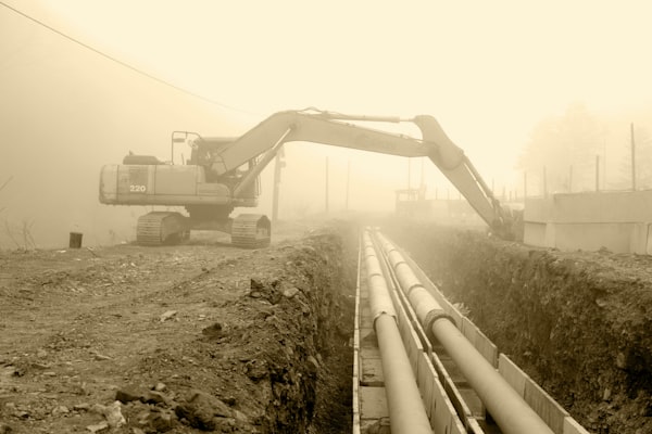 Excavator beside large pipes for trenchless pipe installation